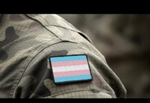 Camouflage military uniform sleeve with a transgender pride flag patch.