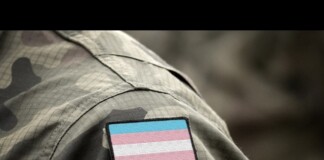Camouflage military uniform sleeve with a transgender pride flag patch.