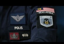 Malaysia Police Investigate Death, Arrest 51 Men Linked to an Alleged “Gay Party” Close-up of police patches on a dark uniform, including a Malaysia flag patch and a POLIS badge on the sleeve.