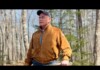 Maine GOP Candidate Cites Noah’s Ark to Deny the Existence of Transgender Youth Older man with a mustache wearing a brown suede jacket and cap stands in a bare forest, looking into the distance.