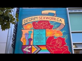 Colorful mural on a building advocating for decriminalization of sex work in California, with raised fists and flowers.