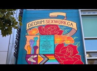 Colorful mural on a building advocating for decriminalization of sex work in California, with raised fists and flowers.
