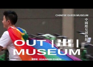 World’s First Chinese LGBTQ Museum Opens in San Francisco’s Chinatown Person walking past a banner wearing a rainbow Pride flag; large white text reads 'OUT MUSEUM' with vertical Chinese text 'CHINESE QUEER MUSEUM' on the right.