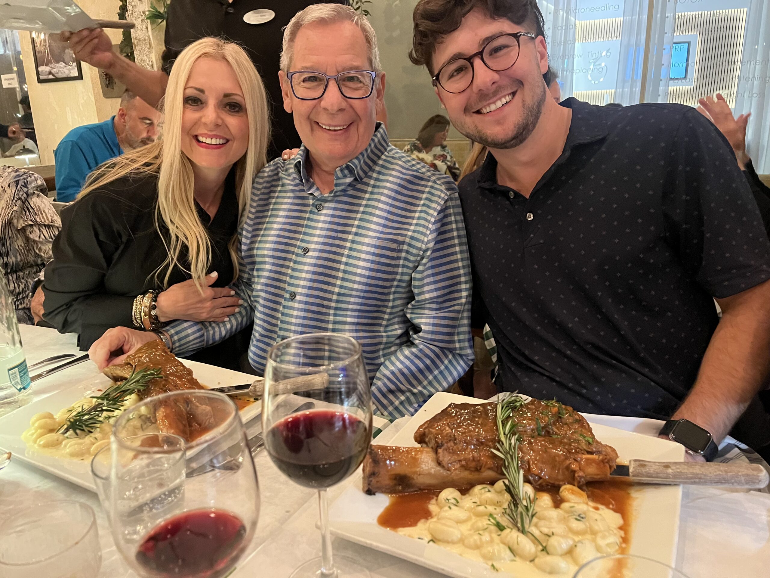Paul Rolli: Ready to Lead Wilton Manors Into Its Next Chapter | Hotspots Magazine Hotspots Magazine Three smiling diners pose at a restaurant table with wine glasses and plates of food in the foreground.
