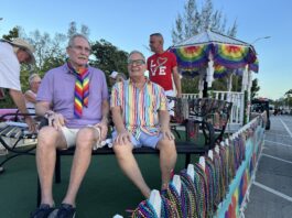 Paul Rolli: Ready to Lead Wilton Manors Into Its Next Chapter People riding on a pride parade float wearing colorful outfits and rainbow accessories, with bead garlands on display behind them.