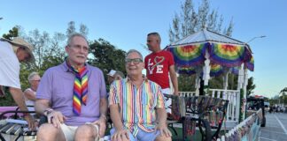 Paul Rolli: Ready to Lead Wilton Manors Into Its Next Chapter People riding on a pride parade float wearing colorful outfits and rainbow accessories, with bead garlands on display behind them.