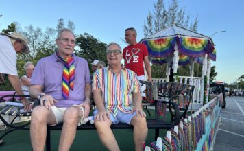 Paul Rolli: Ready to Lead Wilton Manors Into Its Next Chapter People riding on a pride parade float wearing colorful outfits and rainbow accessories, with bead garlands on display behind them.