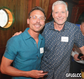What’s Hot South Florida: July 16 – July 29 | Hotspots Magazine Hotspots Magazine Two men posing together at a social event, one in a teal polo and the other in a blue patterned shirt, both smiling and wearing name badges.