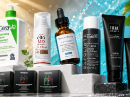 Assorted skincare products on a white pedestal with a bright splashy background, featuring CeraVe cleanser, EltaMD UV Clear, Skinceuticals CE Ferulic, Paula's Choice exfoliant, and Tiëge/Brickell tubes and boxes.
