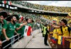 Mexico World Cup Match Overshadowed by Homophobic Chant Energetic soccer fans in green Mexico jerseys chant at a stadium barrier, with Mexican and Ecuadorian flags nearby.