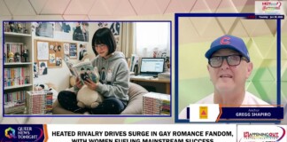 Young person in a gray hoodie reads a manga on a comfy chair, surrounded by shelves of books and a plush toy in a cozy room.