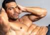Abs After 40: Yes, You Can Still Rock a Strong Core Shirtless muscular man, hands behind head, showing defined abs in a studio portrait.