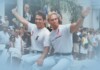 Deep Inside Hollywood: A Bloody Prom, Queer Bodybuilders, and the Return of the ’90s Supers Two men in white T-shirts ride a boat and wave to a cheering crowd at a sunny parade.
