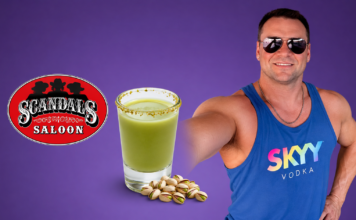 Man in sunglasses and a blue SKYY Vodka tank top poses with a green salted-rim drink and pistachios beside a Scandal's Saloon logo on a purple background.