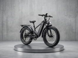Business Profile – Carvelle Bikes: Keeping Wilton Manors Rolling – One Rider at a Time Black electric bike on a round metallic pedestal in a minimalist concrete studio setting.