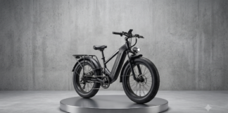 Black electric bike on a round metallic pedestal in a minimalist concrete studio setting.
