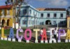 Genre Latino: Veracruz, Mexico Colorful outdoor letters spell Tlacotalpan in front of pastel colonial buildings on a sunny plaza, Veracruz.