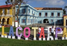 Colorful outdoor letters spell Tlacotalpan in front of pastel colonial buildings on a sunny plaza, Veracruz.