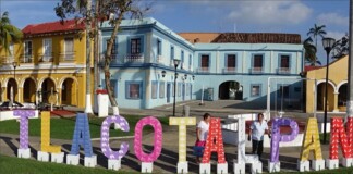 Colorful outdoor letters spell Tlacotalpan in front of pastel colonial buildings on a sunny plaza, Veracruz.