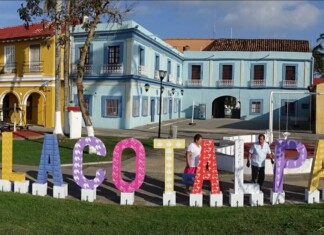 Genre Latino: Veracruz, Mexico Colorful outdoor letters spell Tlacotalpan in front of pastel colonial buildings on a sunny plaza, Veracruz.
