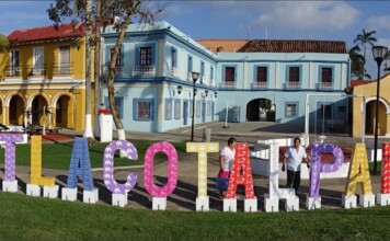 Colorful outdoor letters spell Tlacotalpan in front of pastel colonial buildings on a sunny plaza, Veracruz.