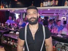 Hot Bartender – Mohammad Balaoni Bearded bartender wearing a black shirt and suspenders behind a busy bar.