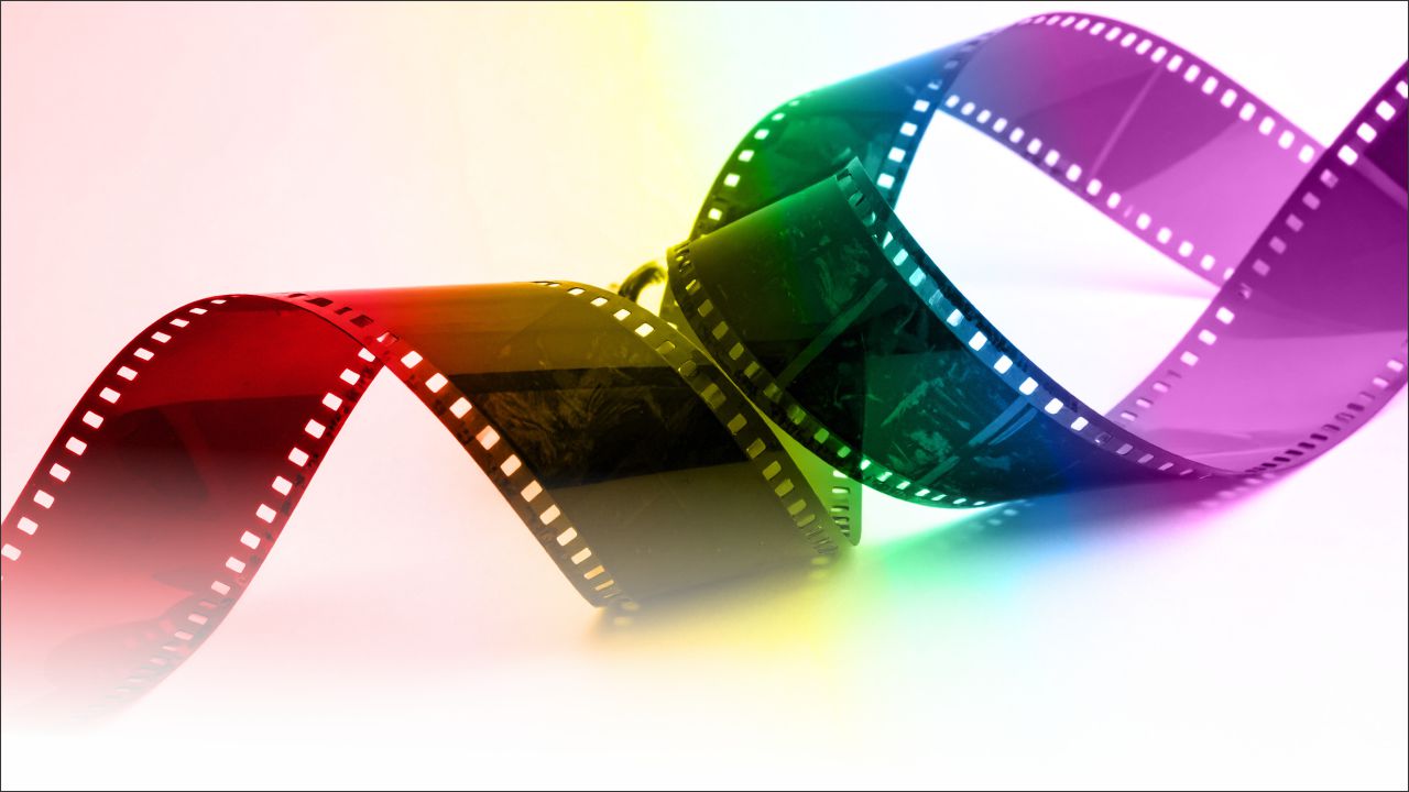 Rainbow-colored film strip curling across a light background, suggesting cinema or video.