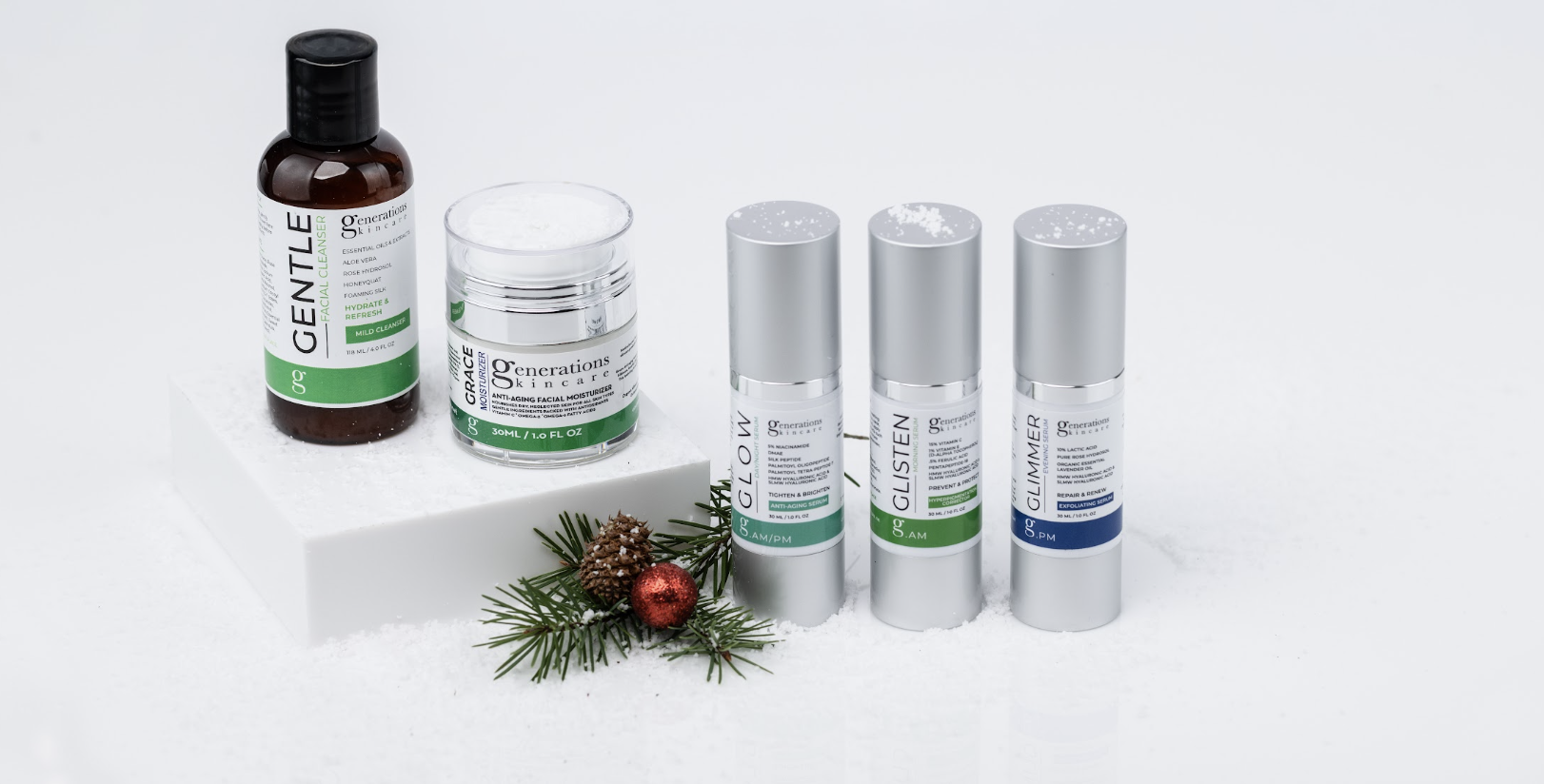 Assorted Generations skincare products displayed on a white snowy surface, including a cleanser bottle, moisturizer jar, and three silver serum bottles with a small pine sprig and red ornament nearby.