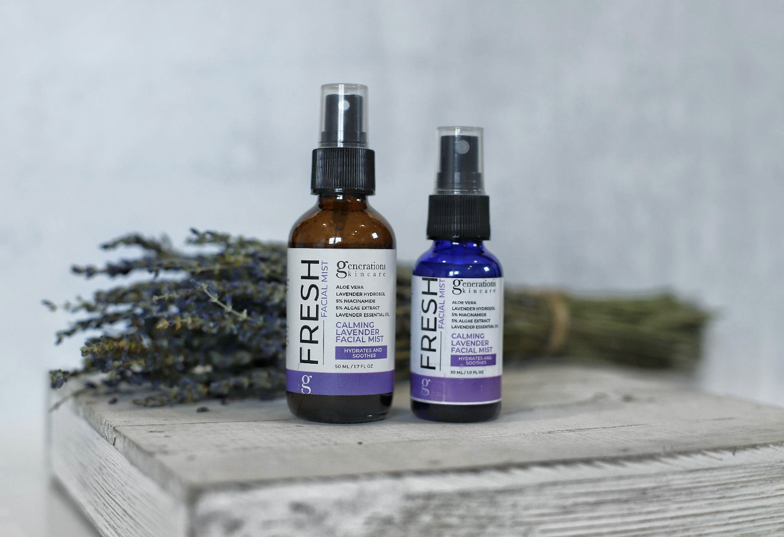 Two spray bottles labeled 'FRESH' on a rustic wooden surface with a lavender bouquet in the background (calming facial mist).